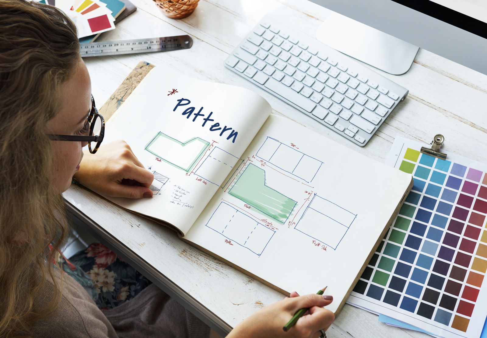 Designer sketching brand identity ideas in a notebook beside colour swatches