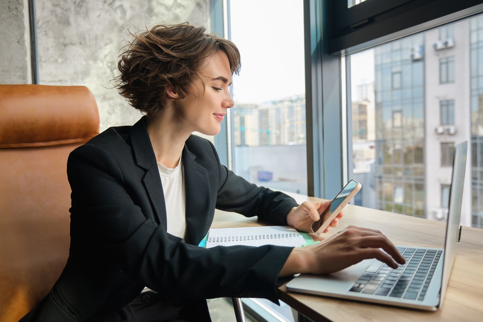 Executive working on her laptop and phone in a city office