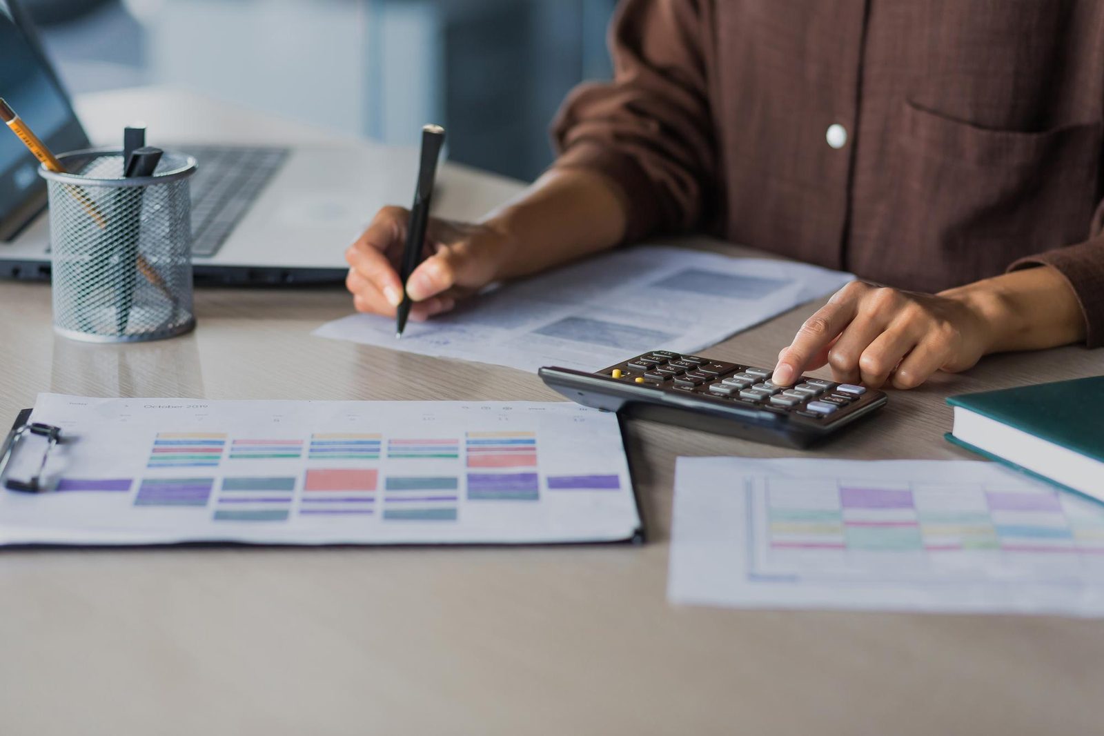 Hands using a calculator over budget planning sheets