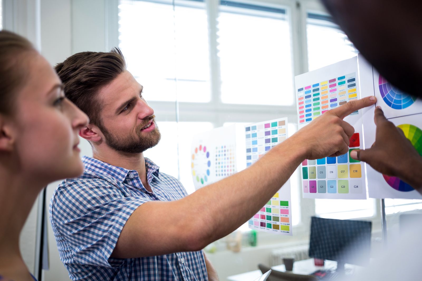Designers comparing colour charts pinned to a wall
