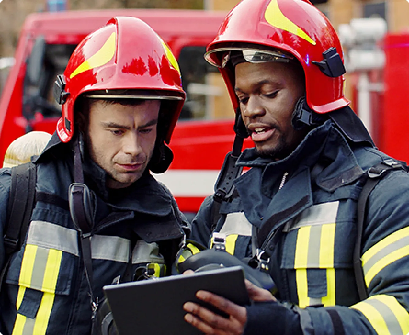 Two firefighters checking a tablet on the incident ground