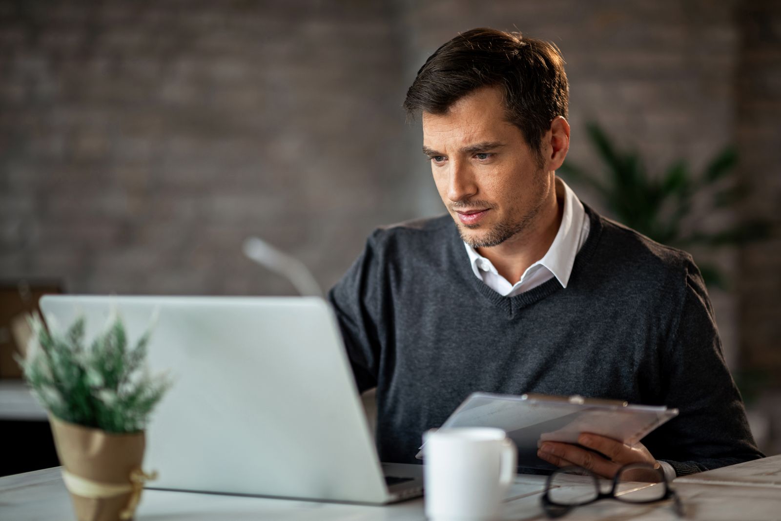 Man entering figures from printed reports into his computer