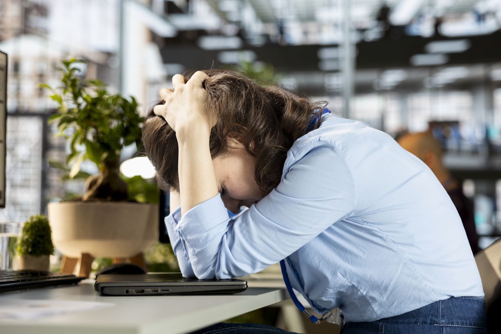 Overwhelmed professional at her desk with her head in her hands
