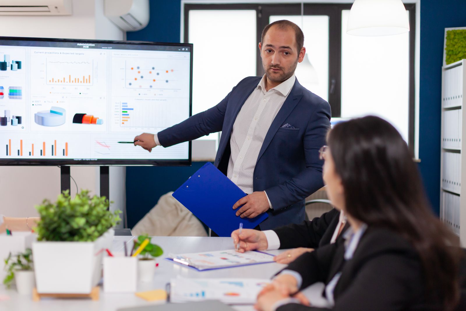 Manager presenting website results on a screen to colleagues