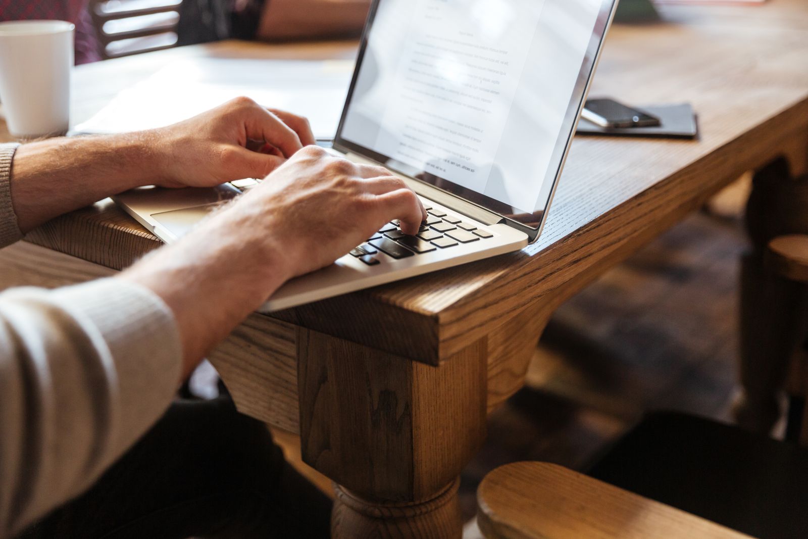 Writer typing on a laptop at a wooden desk